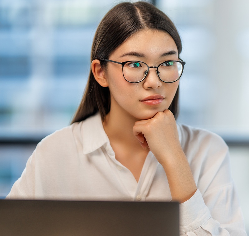 A healthcare administration professional reviews reports and schedules on a computer in a bright office, managing operations and ensuring efficient coordination within a medical facility.