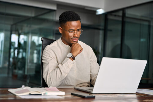 a man sitting at a desk looking at a laptop